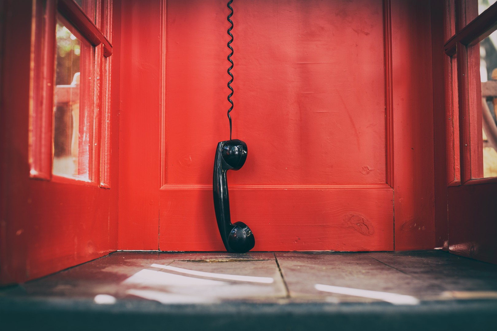 Black,handset,hanging,in,a,red,telephone,box.,telephone,receiver
