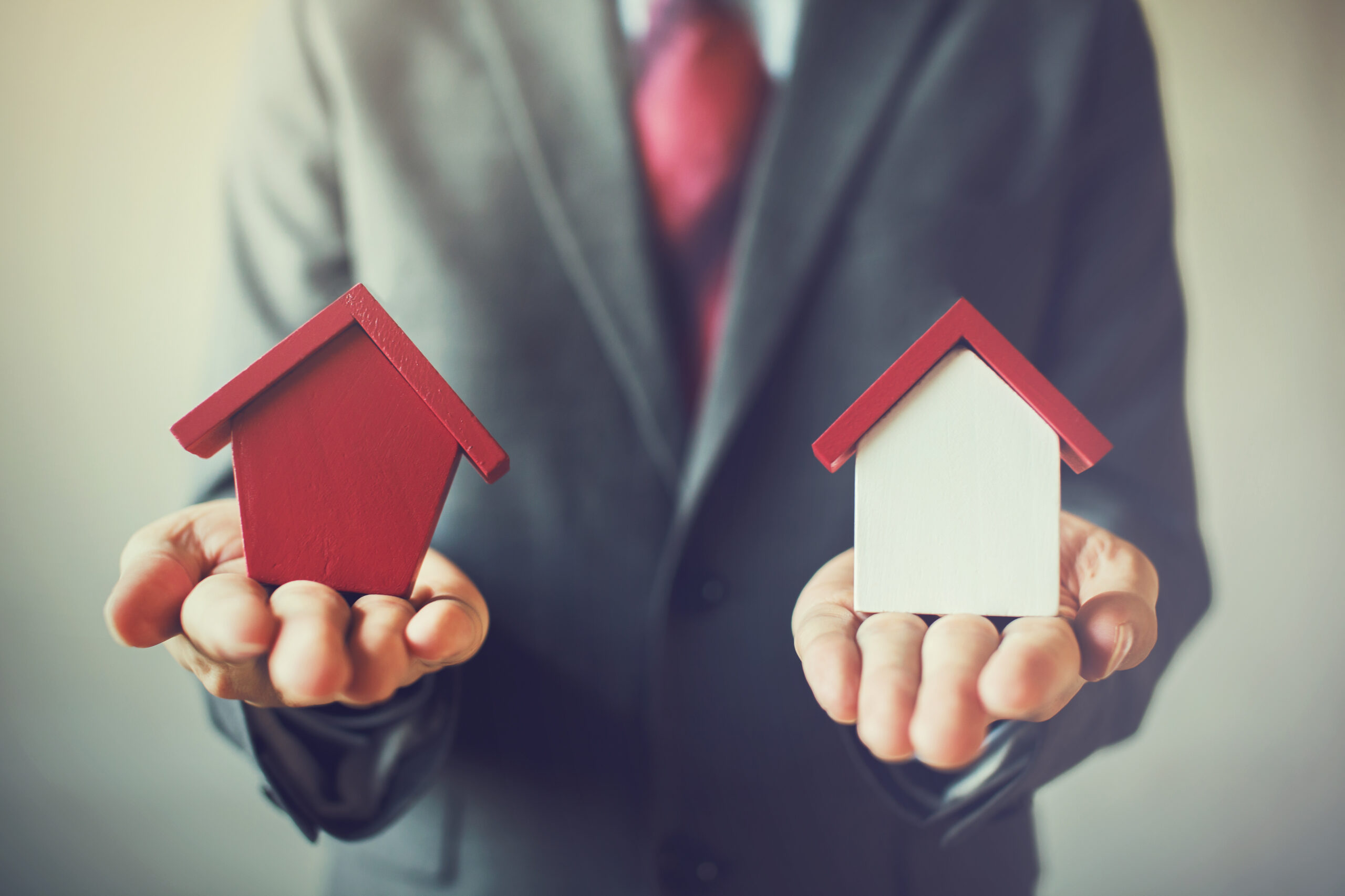 Businessman,holding,two,houses,and,can,not,decide,choosing,the